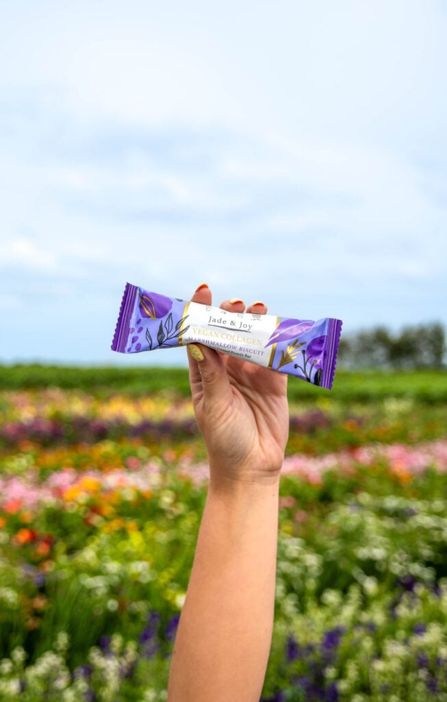Jade & Joy Vegan Collagen Protein Bar in a flower field